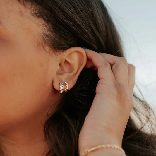 Brown and white checkered gold hoops worn on an ear