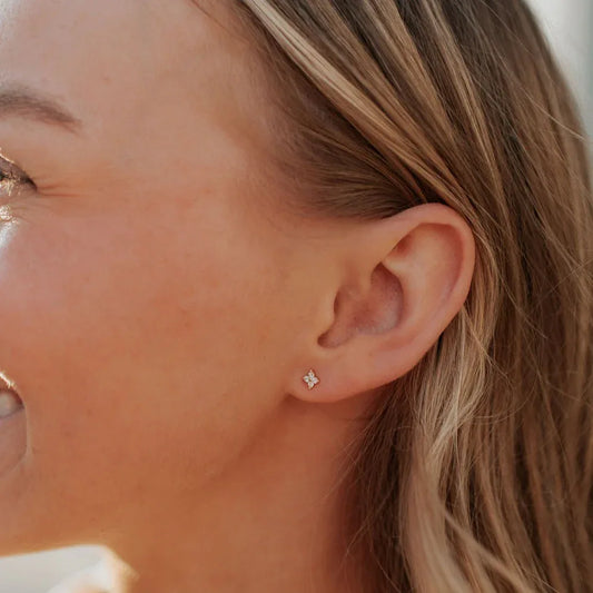 Margot gold flower stud earring with clear stones, worn on the earlobe