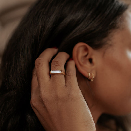 Gold-tone mother-of-pearl bar ring worn on a finger