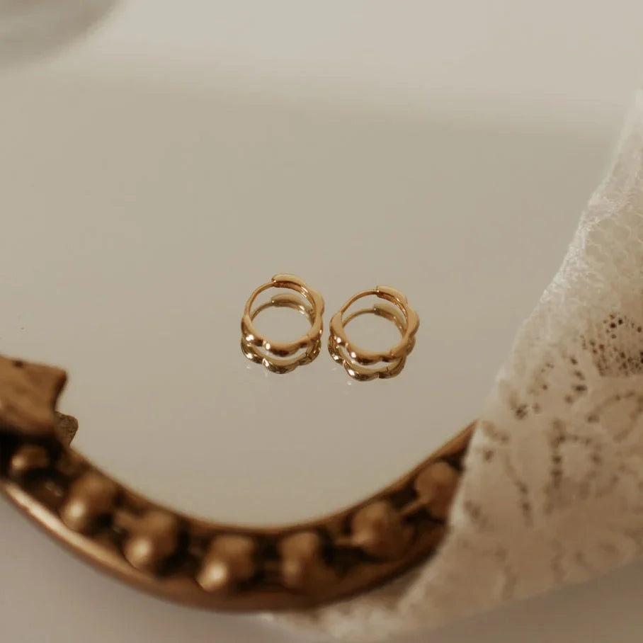 Pair of gold floral hoop earrings shown upright, revealing their layered petal-like edges.