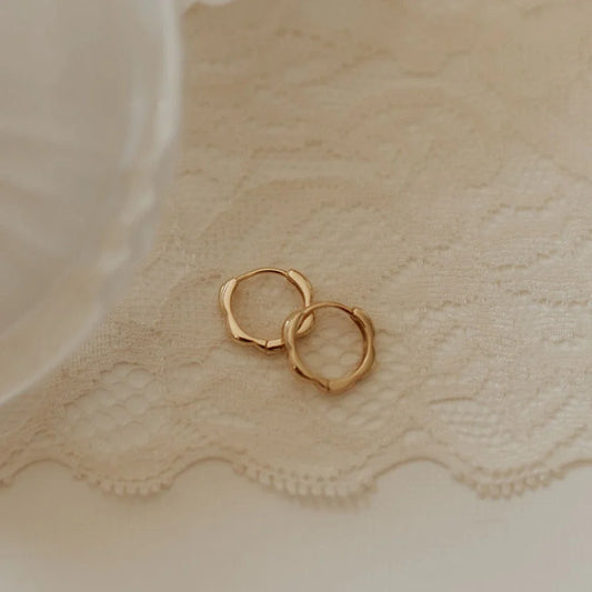 Pair of gold floral hoop earrings shown from above.