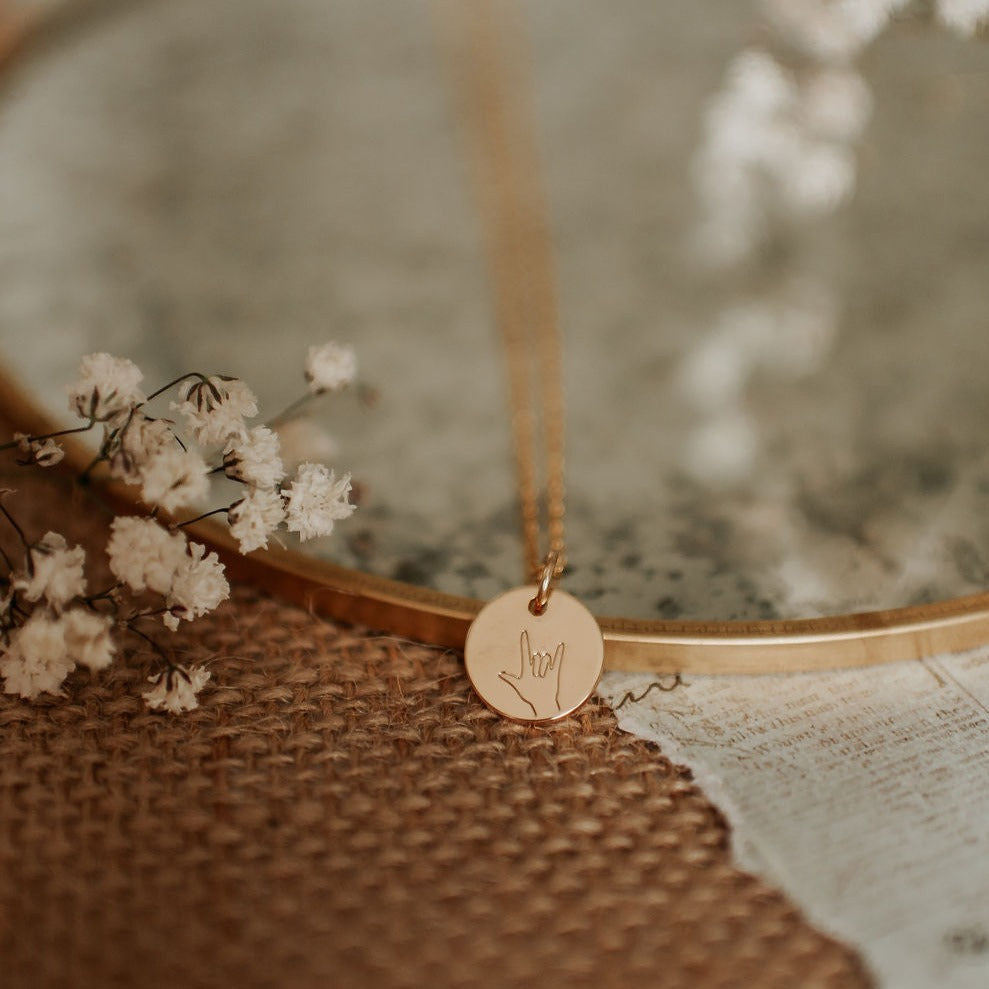 Gold disc pendant necklace engraved with an ASL I love you hand sign