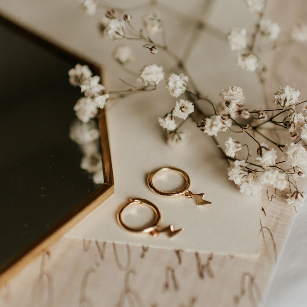 Pair of gold vermeil lightning bolt huggie hoop earrings, viewed from above.