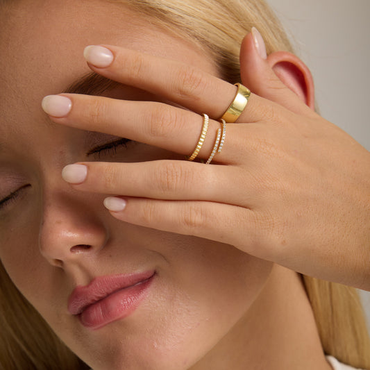 Gold spiral wrap ring on hand with stacked rhinestone bands, adjustable fit