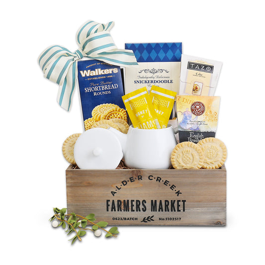 Gift basket tray with striped ribbon bow, white candle holder, tea packets and shortbread cookies