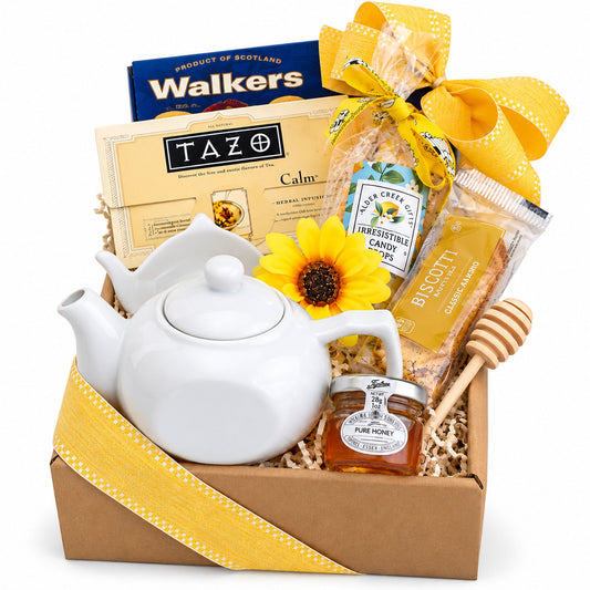 Tea gift basket with white ceramic teapot, honey jar, and assorted tea and biscuits