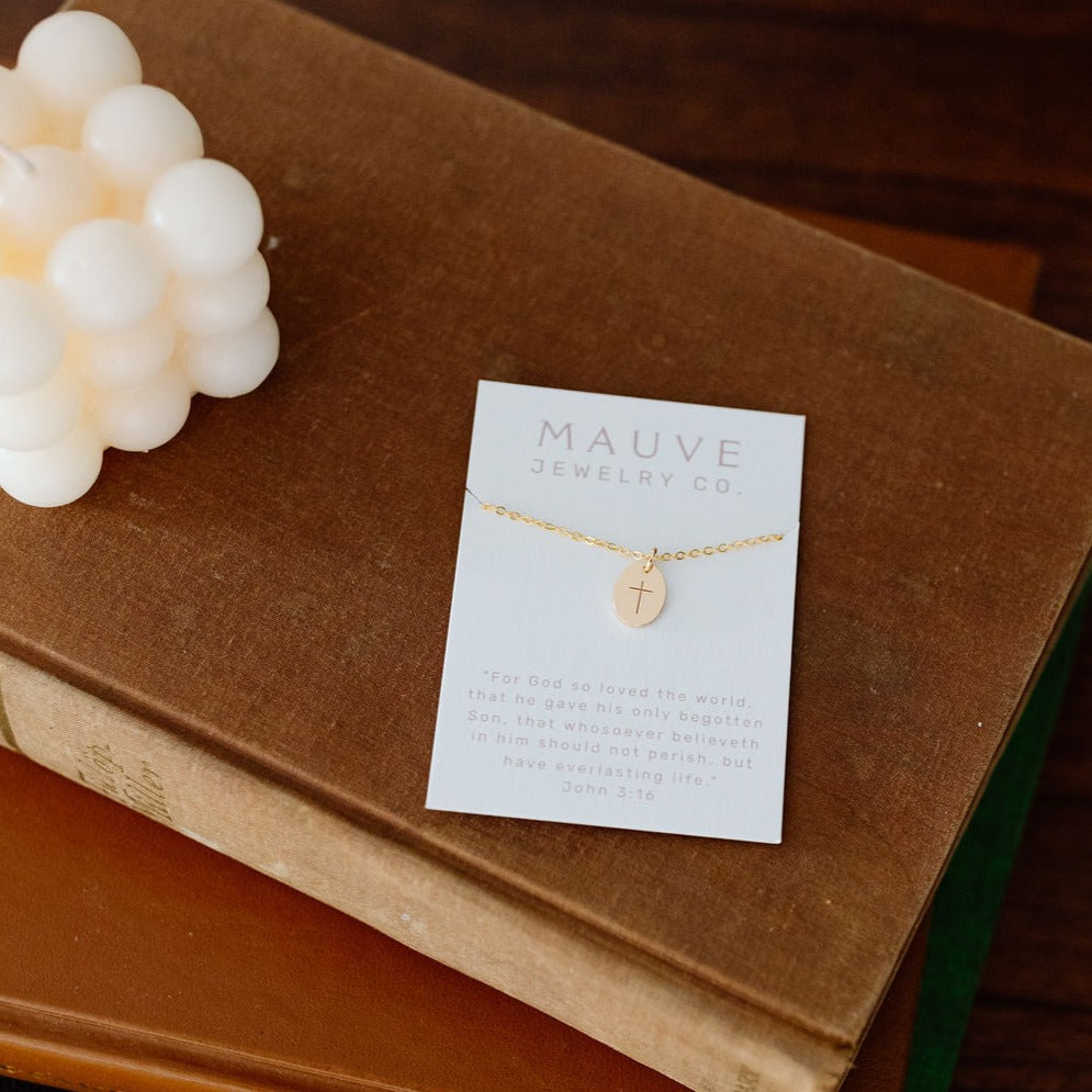 Gold cross pendant necklace displayed on a jewelry card.