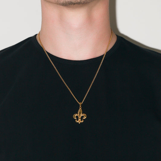 Gold pendant necklace with fleur-de-lis charm worn at the center of the neck