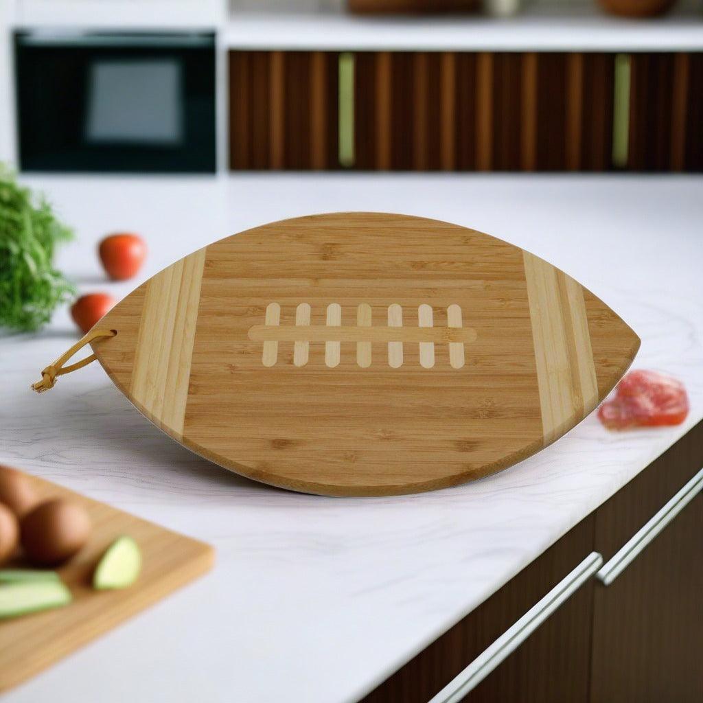 Football-shaped wooden cutting board with white football graphic and handle tie