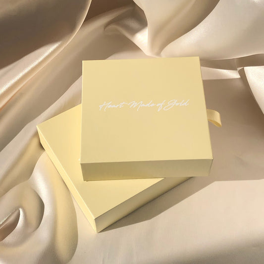 Cream gift boxes stacked with satin ribbon, cursive logo on top lid