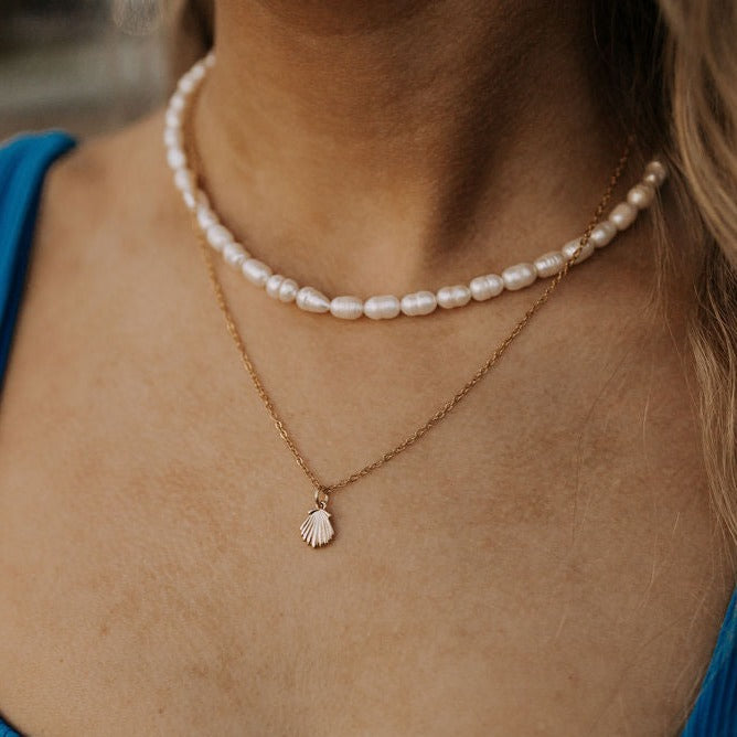 Gold shell pendant necklace layered with a white pearl strand