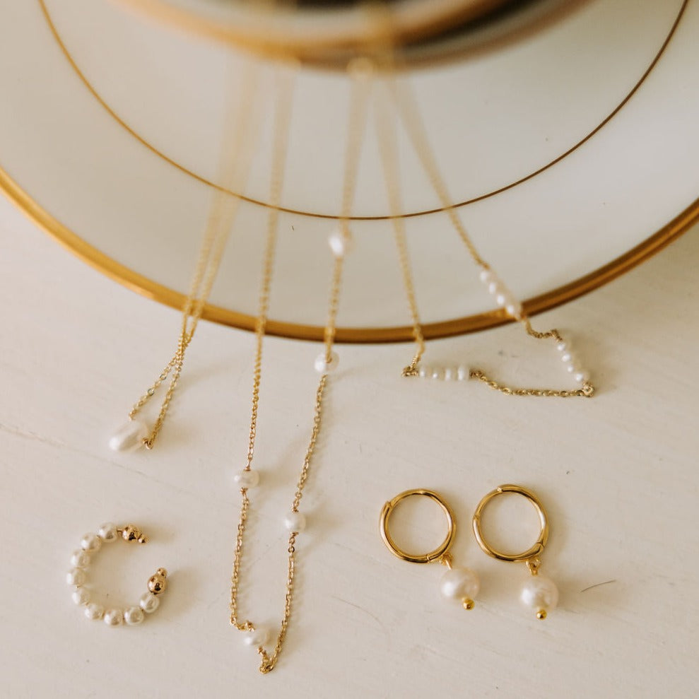 Fine gold-tone necklace with spaced white pearls, displayed with pearl earrings