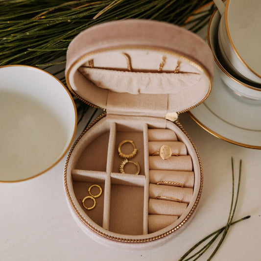 Open round jewelry case with ring rolls, divided storage, and gold-tone jewelry