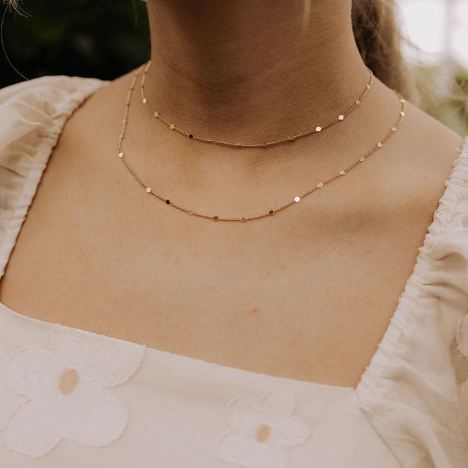 Nora gold-filled necklace with spaced round accents worn in a two-layer style.