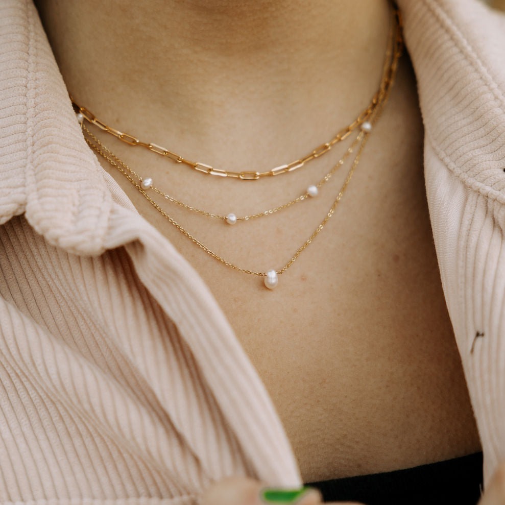 Gold pearl necklace with spaced pearls, worn in a layered stack