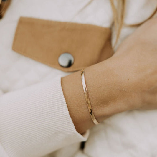 Slim gold-filled herringbone bracelet worn around the wrist.