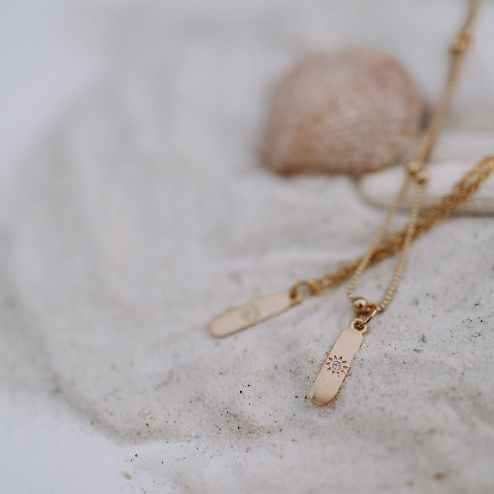 Close-up of the gold-tone chain and slim sunburst pendant