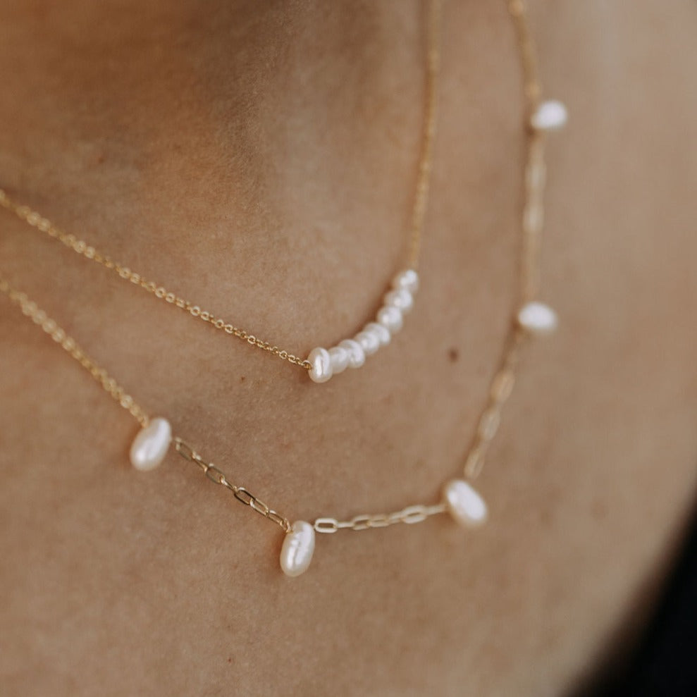 Close-up of a gold chain and curved row of freshwater pearls