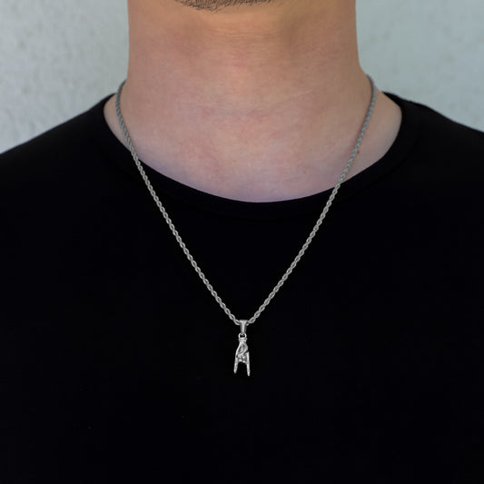 Silver hand horn pendant necklace on a chain, worn at the collar.