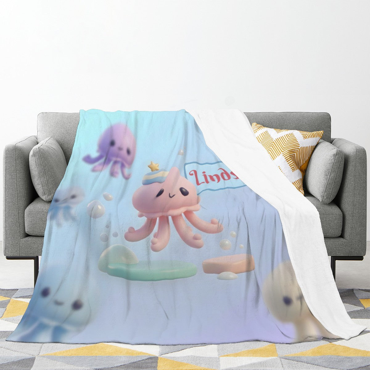 Octopus-themed light blue blanket draped on couch, featuring octopus characters and Lindsey print
