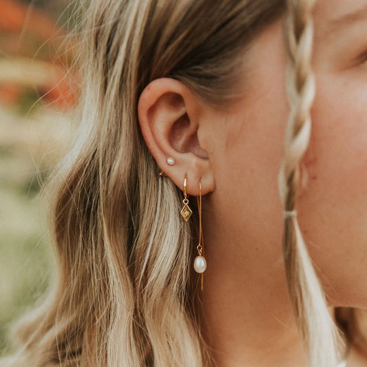 Gold Nova Hoops with dangling diamond charms, worn on an ear