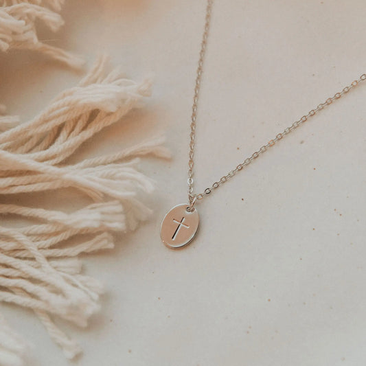 Silver cross pendant necklace with a fine chain and round medallion.