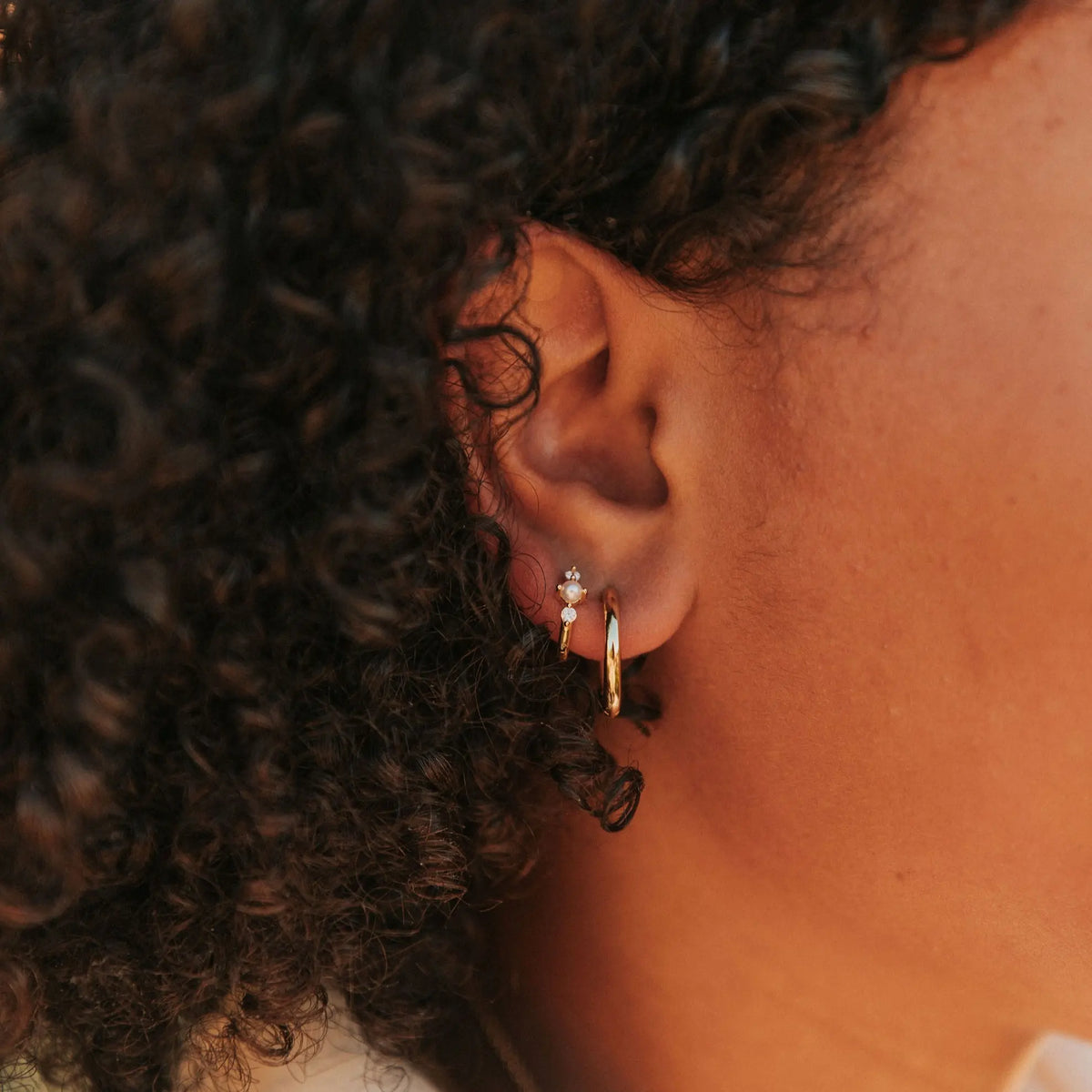 Gold vermeil hoop earring with pearl accents worn on an ear