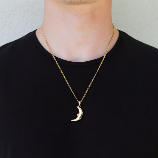 Gold crescent moon pendant necklace worn at the neck on a thin link chain.