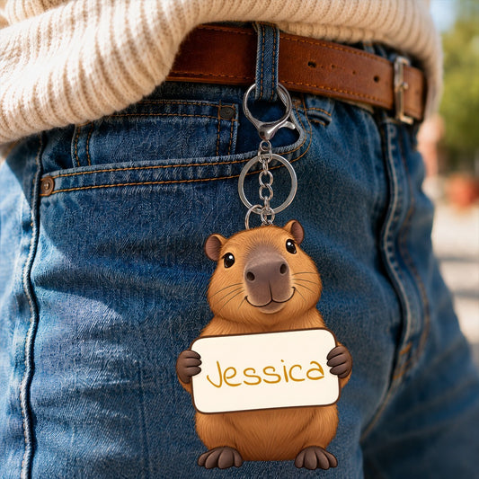 Capybara plush keychain hanging from a denim belt with a white name tag reading Jessica