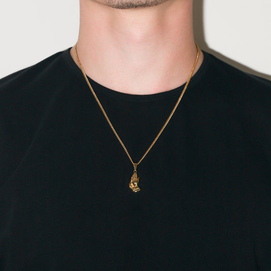Gold praying hands pendant necklace on curb chain, worn at the collar