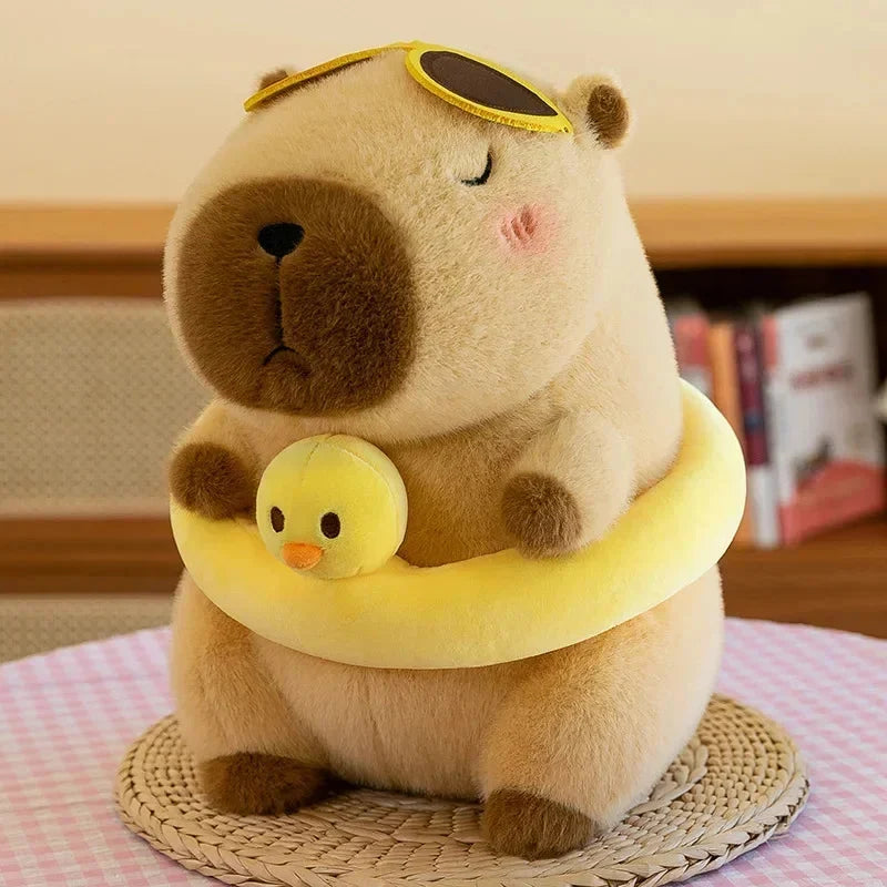Tan capybara plush with yellow neck ring holding small chick