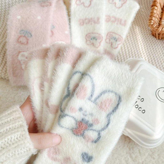 Bunny socks in white with blue and pink heart-and-paw print design, fuzzy knit texture.