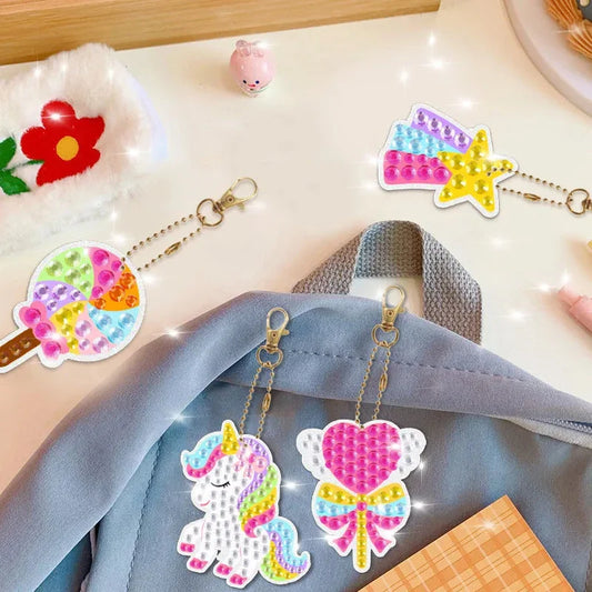 Unicorn-themed diamond painting keychain charms with chains on a fabric bag.