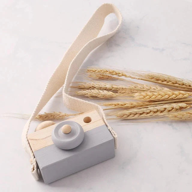 Wooden camera pendant toy with beige strap and grey front, wooden top and circular button
