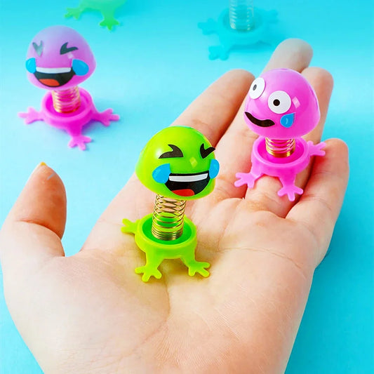 Hand holding pink, green, and purple spring elf toys with face stickers and coils