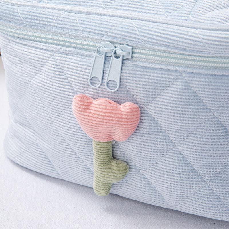 Blue flower makeup bag with zip top, pink heart-shaped charm on strap
