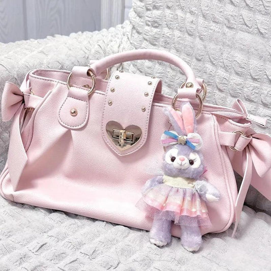 Pink heart-lock handbag with bow ties, studded panel, and bunny plush keychain charm