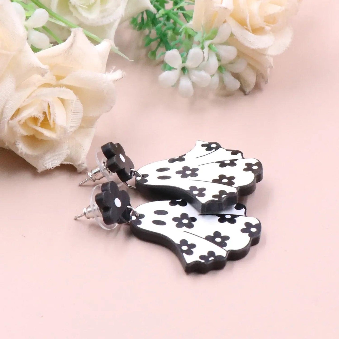 Ghost dangle earrings with black flower studs and white floral ghost charms, side view
