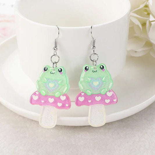 Frog acrylic earrings with green frog charms, pink skirt with heart pattern, and silver hooks
