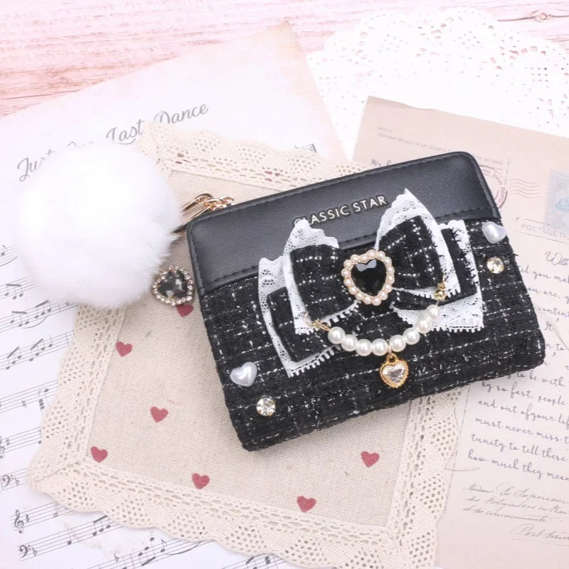 Black quilted wallet with bow and heart charms, pearl trim, and gold-tone zipper
