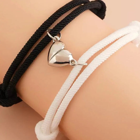 Two braided rope bracelets, black and white, with silver heart charm on clasp
