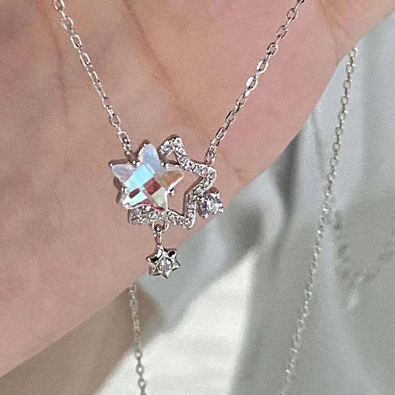 Star pendant necklace with silver-tone chain, iridescent rhinestone star cluster, and dangling charm