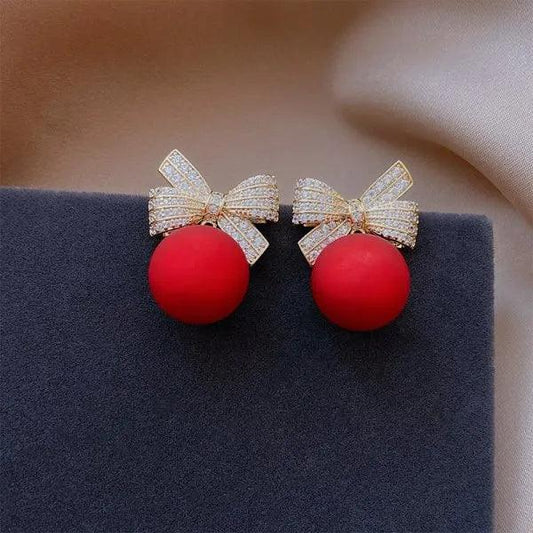 Gold-tone bow stud earrings with red ball ornaments and rhinestone sparkle