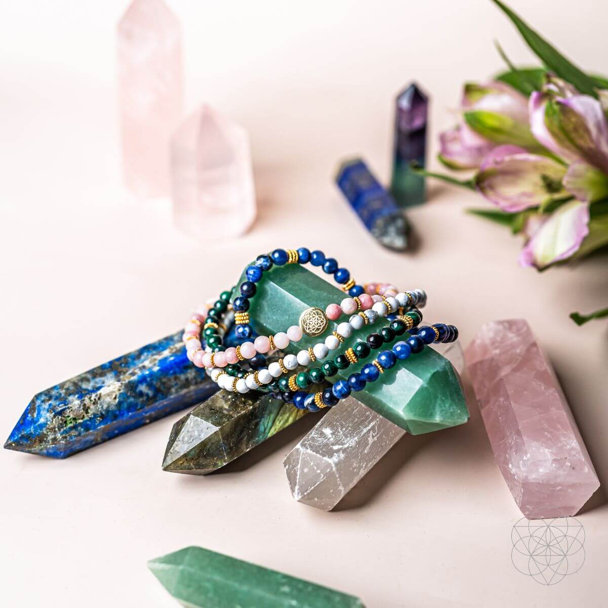 Beaded bracelets with blue, green, white, and pink stones beside crystal points