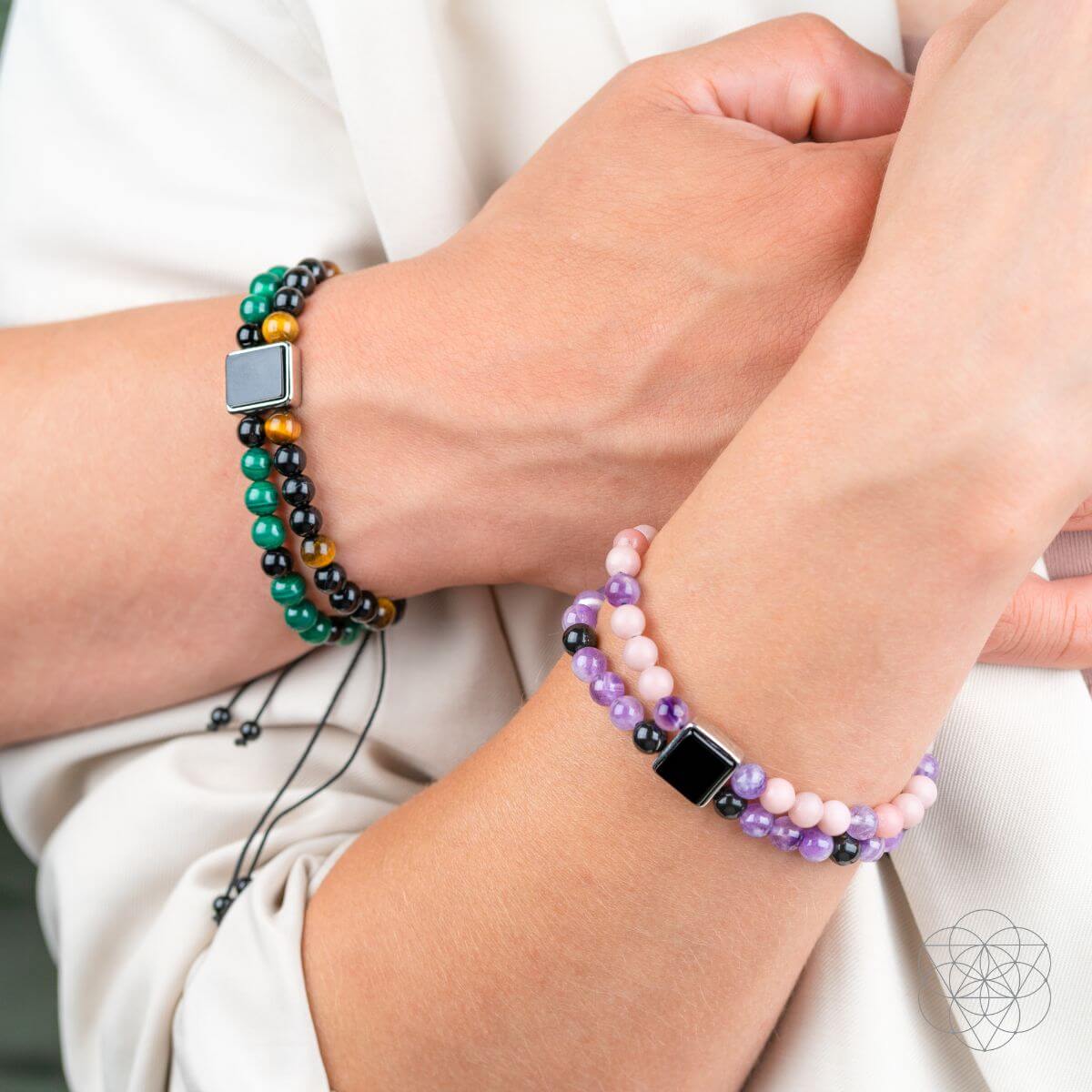 Two beaded bracelets on wrists: black-green with square clasp and purple with square clasp