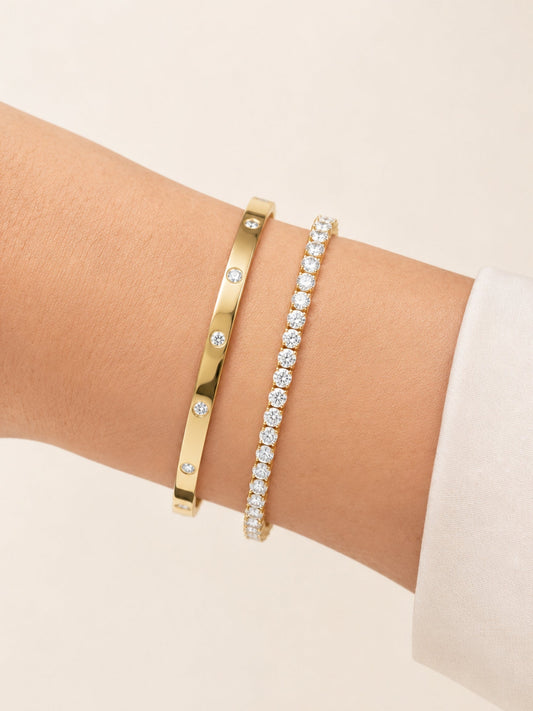 Gold diamond bangle with evenly spaced stones, worn on wrist