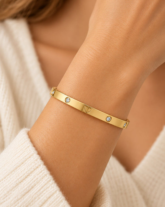Gold-tone bangle bracelet with heart cutout and two round clear stones