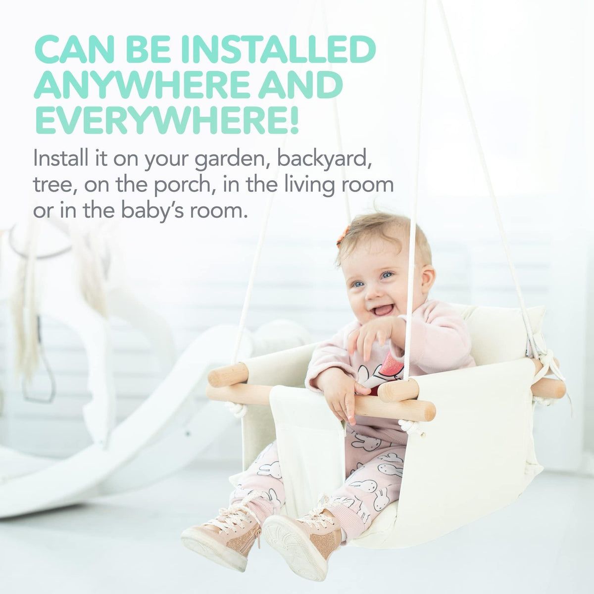White canvas baby hanging swing with wooden dowels and smiling toddler in seat