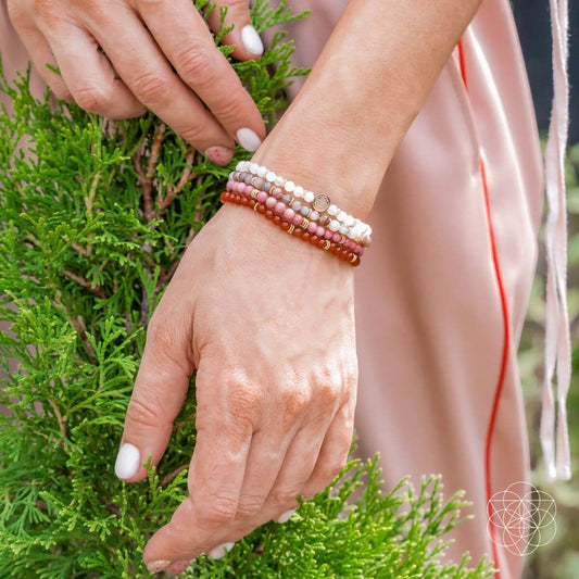 Beaded bracelet set on wrist featuring white, pink, and red beads with gold details