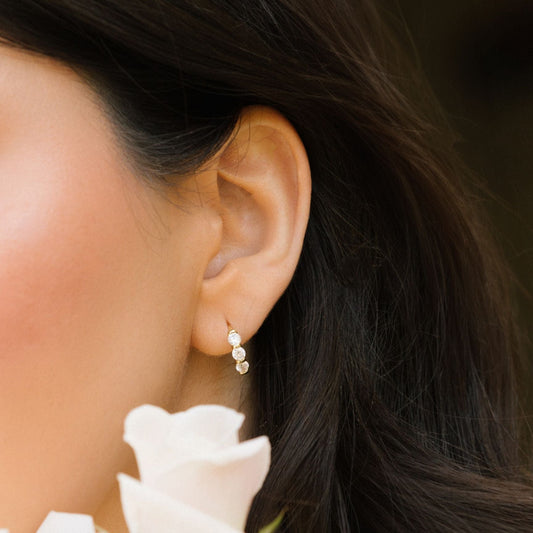 Gold huggie hoop earring with three round clear stones